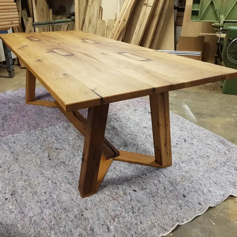 Ein hellfarbiger Holztisch mit natürlicher Kante und dunklen Intarsien