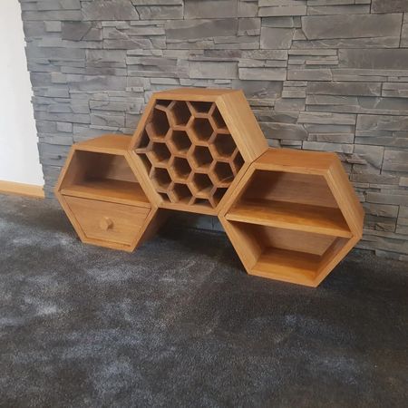 Ein modulares, sechseckiges Eichenmöbelstück mit Weinregal, Schublade und Ablagefläche, das auf einem Teppichboden steht.