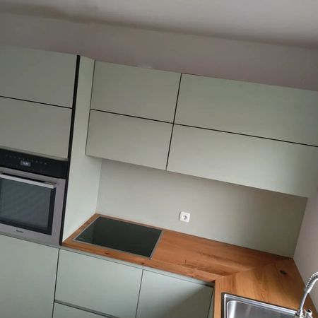 Eine moderne Küche mit salbeigrünen, flächenbündig eingebauten Schränken