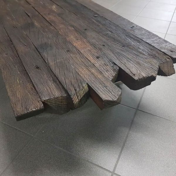 Eine Couchtischplatte aus recycelten, dunkelbraunen Holzplanken