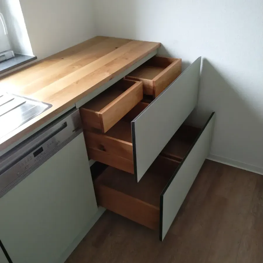 Küchenschränke mit einer Arbeitsplatte aus Holz und zwei offenen Schubladen