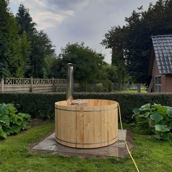 Ein hölzerner Whirlpool mit einem Kaminofen aus Metall