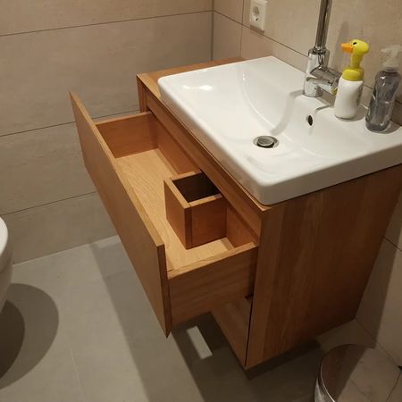 Ein moderner Badezimmerwaschtisch aus Holz mit weißem Waschbecken und einer offenen Schublade