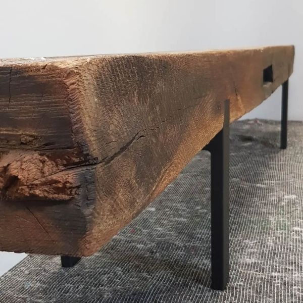 Eine rustikale Holzbank aus einem dicken, verwitterten Holzbalken