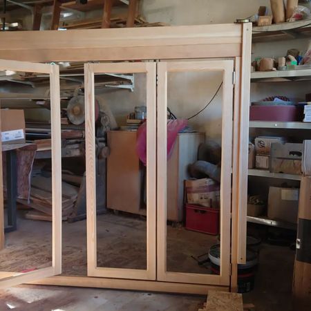 In einer Holzwerkstatt steht zwischen Werkzeugen, Materialien und Lagerraum eine Holzrahmenkonstruktion