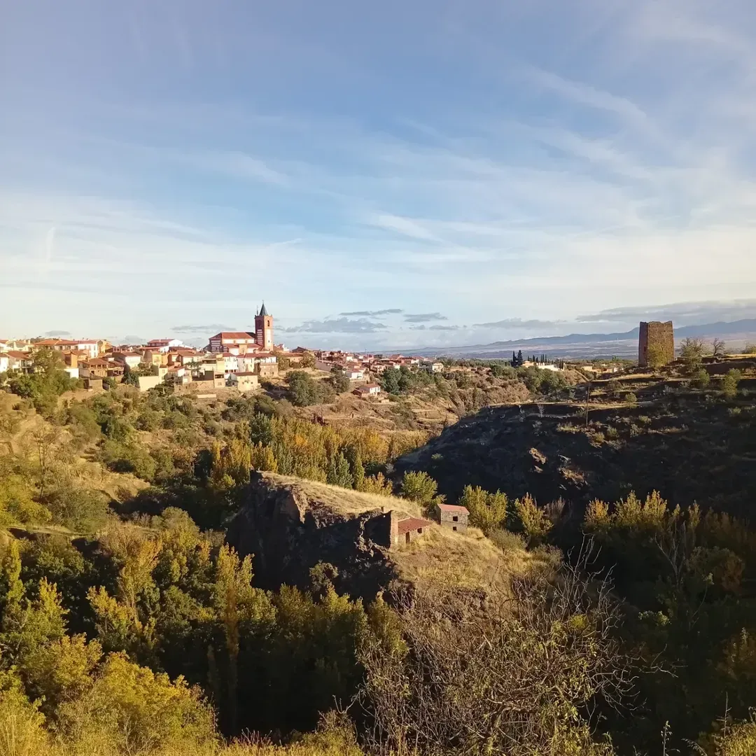 Grupo de personas caminando en una zona montañosa bajo un cielo nublado con luz solar, sonriendo.