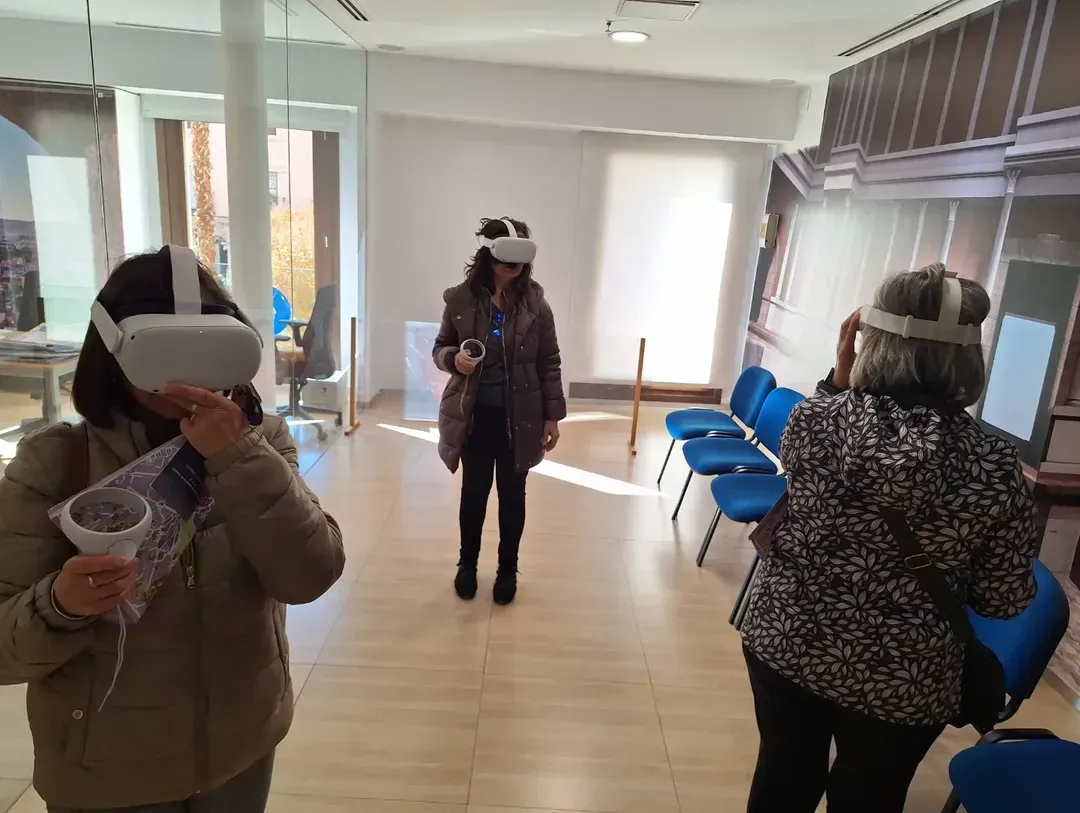 Tres personas que usan gafas de realidad virtual en una habitación, interactuando con contenido virtual.