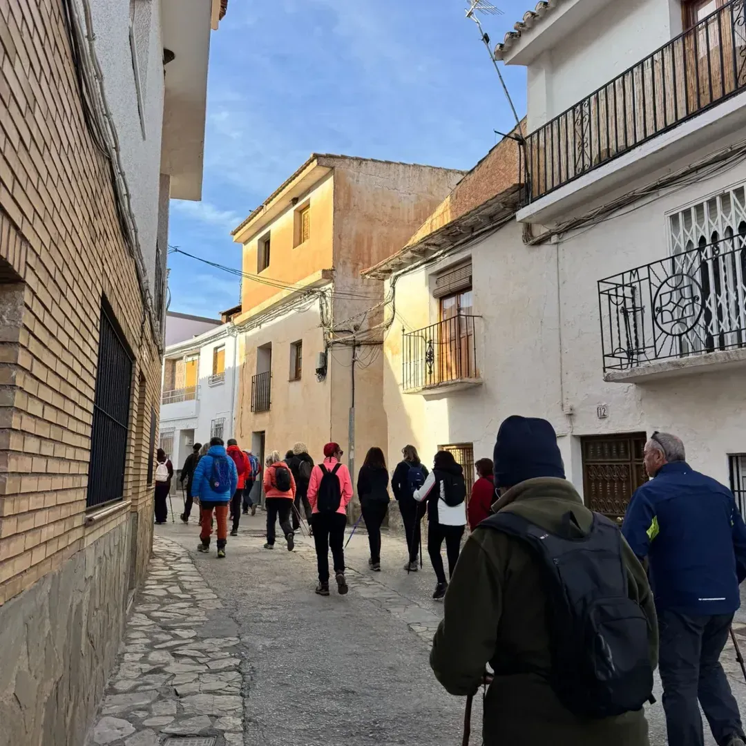 Gente caminando por una calle estrecha en una ciudad europea con pavimento de piedra y edificios a ambos lados.