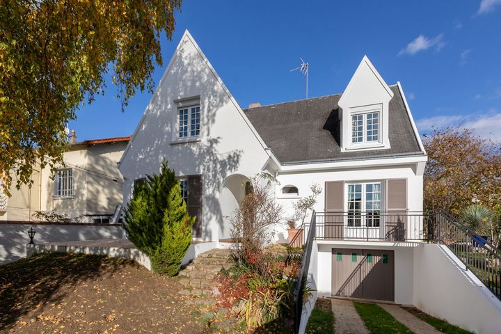Bâtiment moderne avec une façade sombre et texturée, des baies vitrées et de hautes herbes ornementales au premier plan.