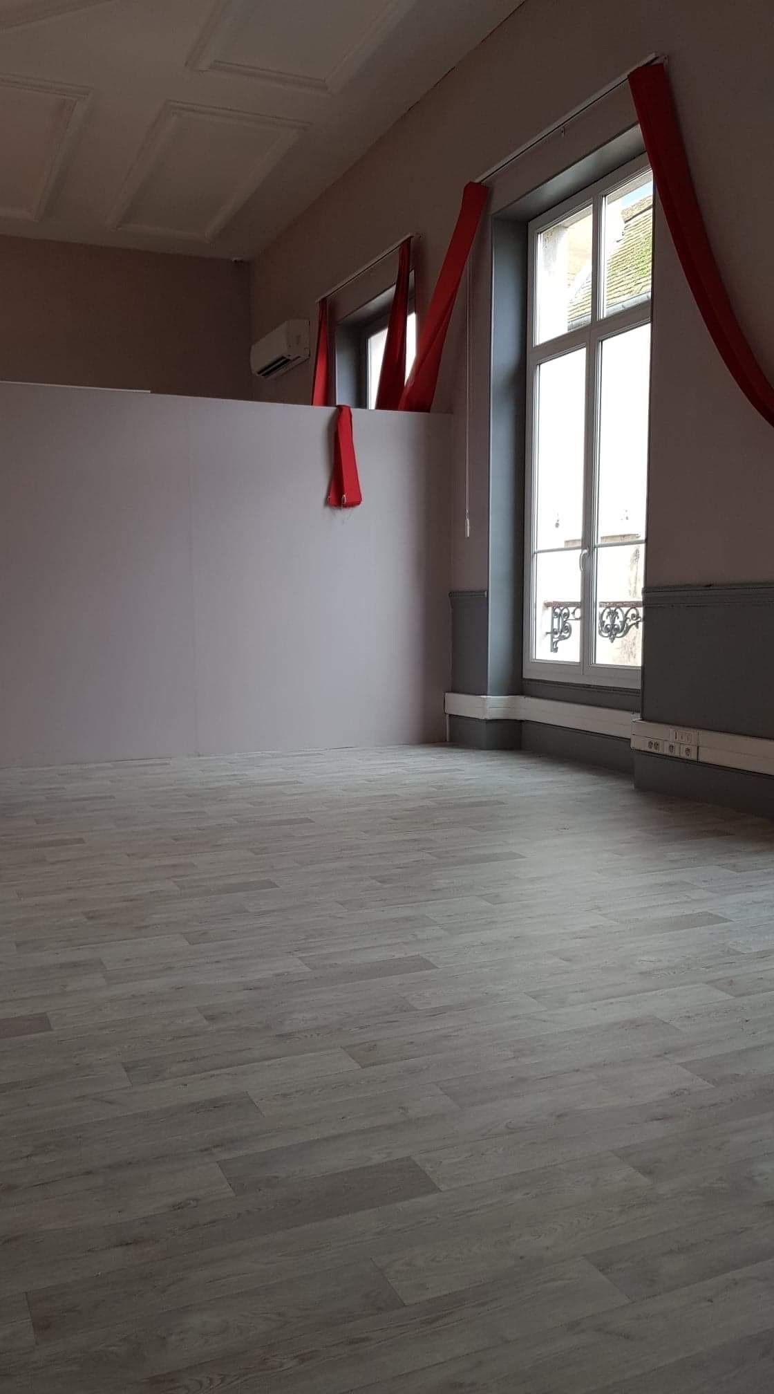 Vue en contre-plongée d'une pièce lumineuse et vide, dotée d'un parquet en bois naturel clair.