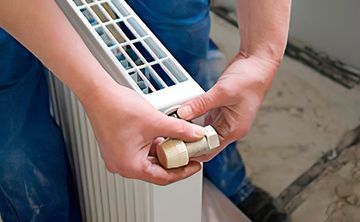 Una persona está ajustando un termostato en un radiador.