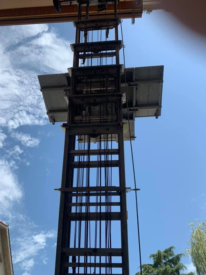 Estructura de ascensor contra un cielo azul, marco de metal alto con cables y una plataforma.
