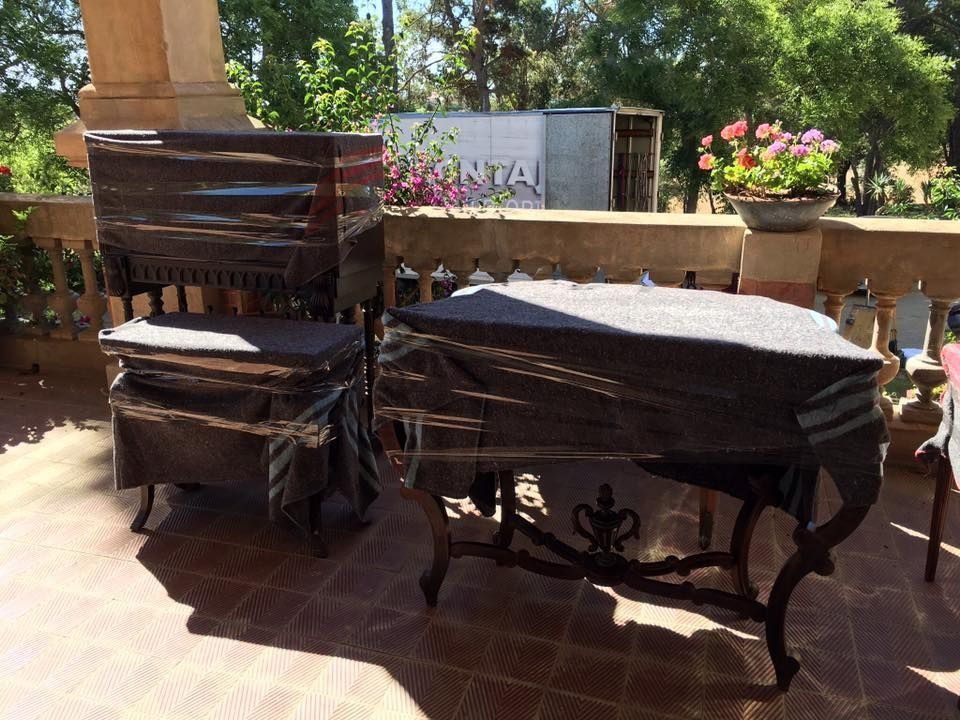 Mesa y silla, envueltas en plástico negro, en una terraza soleada.