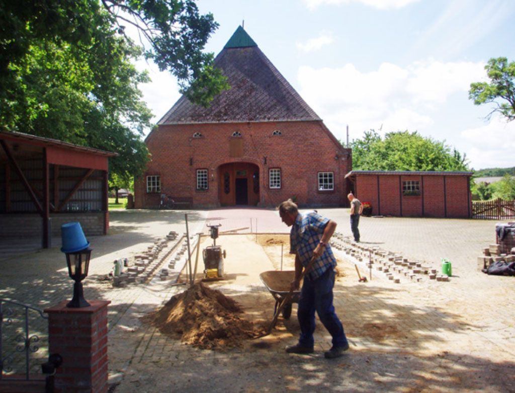 Ein Mann schiebt eine Schubkarre vor einem großen Backsteingebäude
