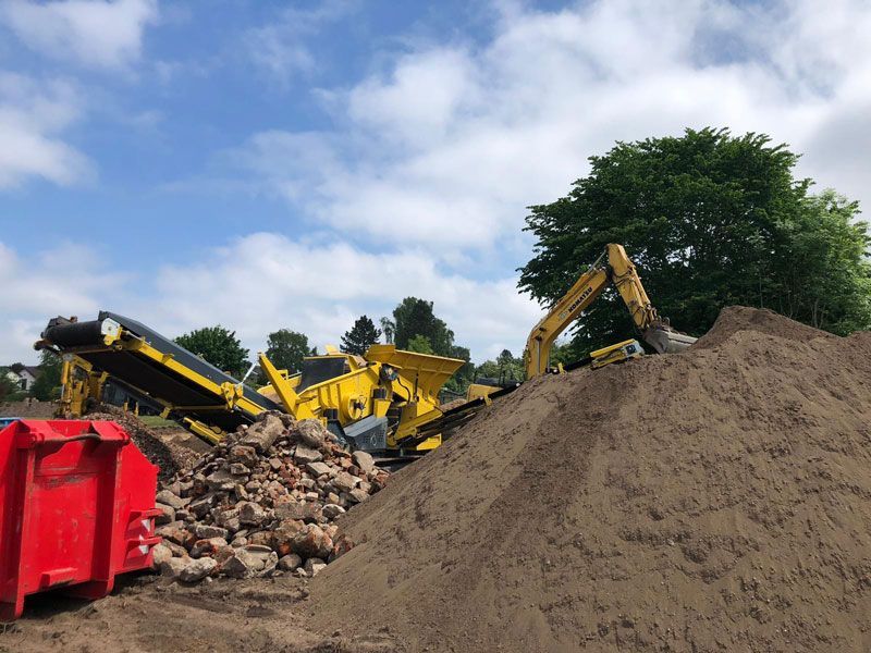 Ein Erdhaufen mit einem gelben Bagger im Hintergrund