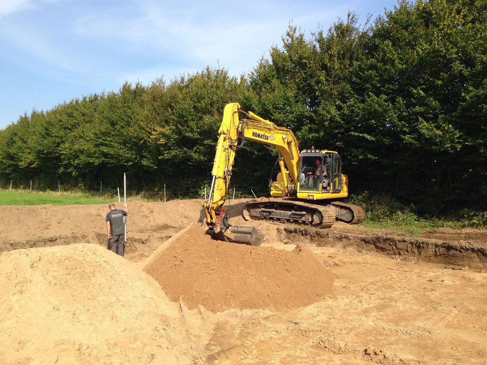 Ein gelber Bagger bewegt Erde auf einem Feld