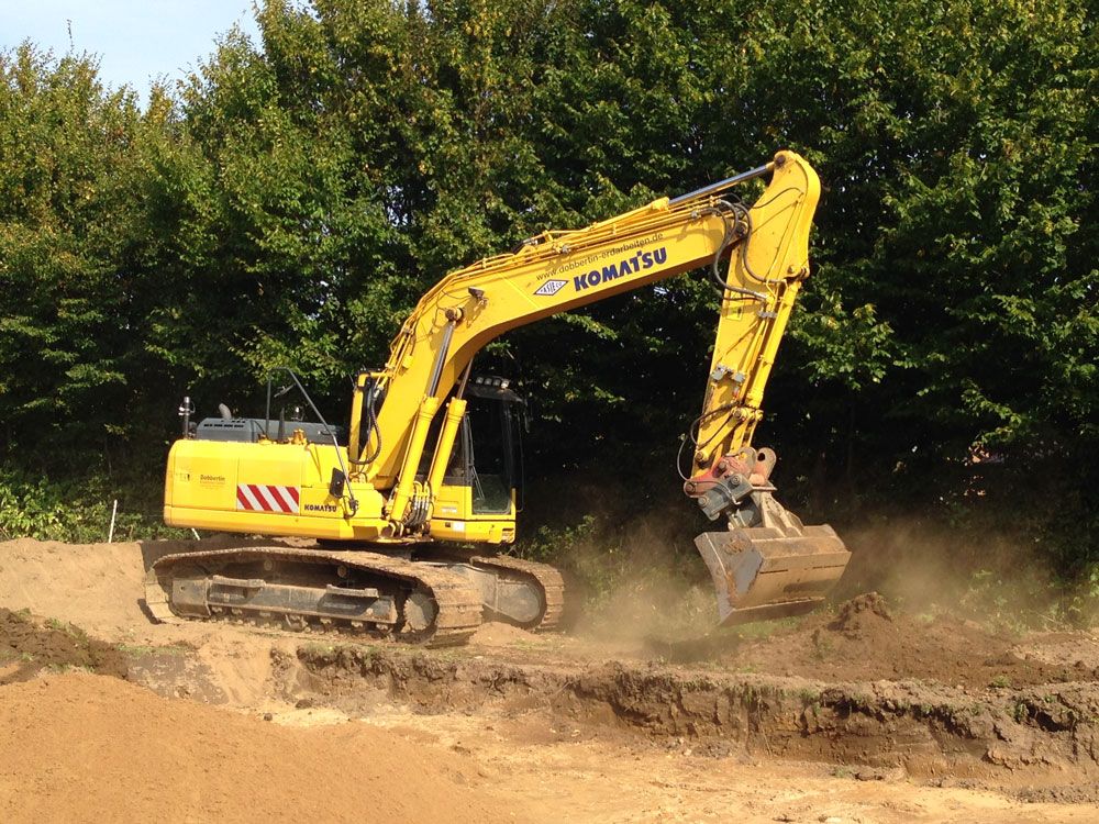 Ein gelber Komatsu-Bagger bewegt Erde auf einem Feld