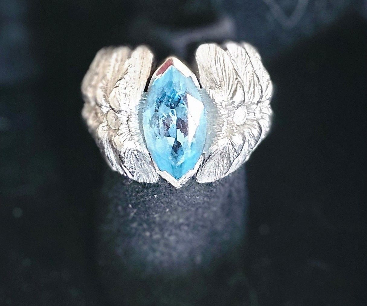 Silberring mit einem blauen, facettierten Edelstein in Flügelform