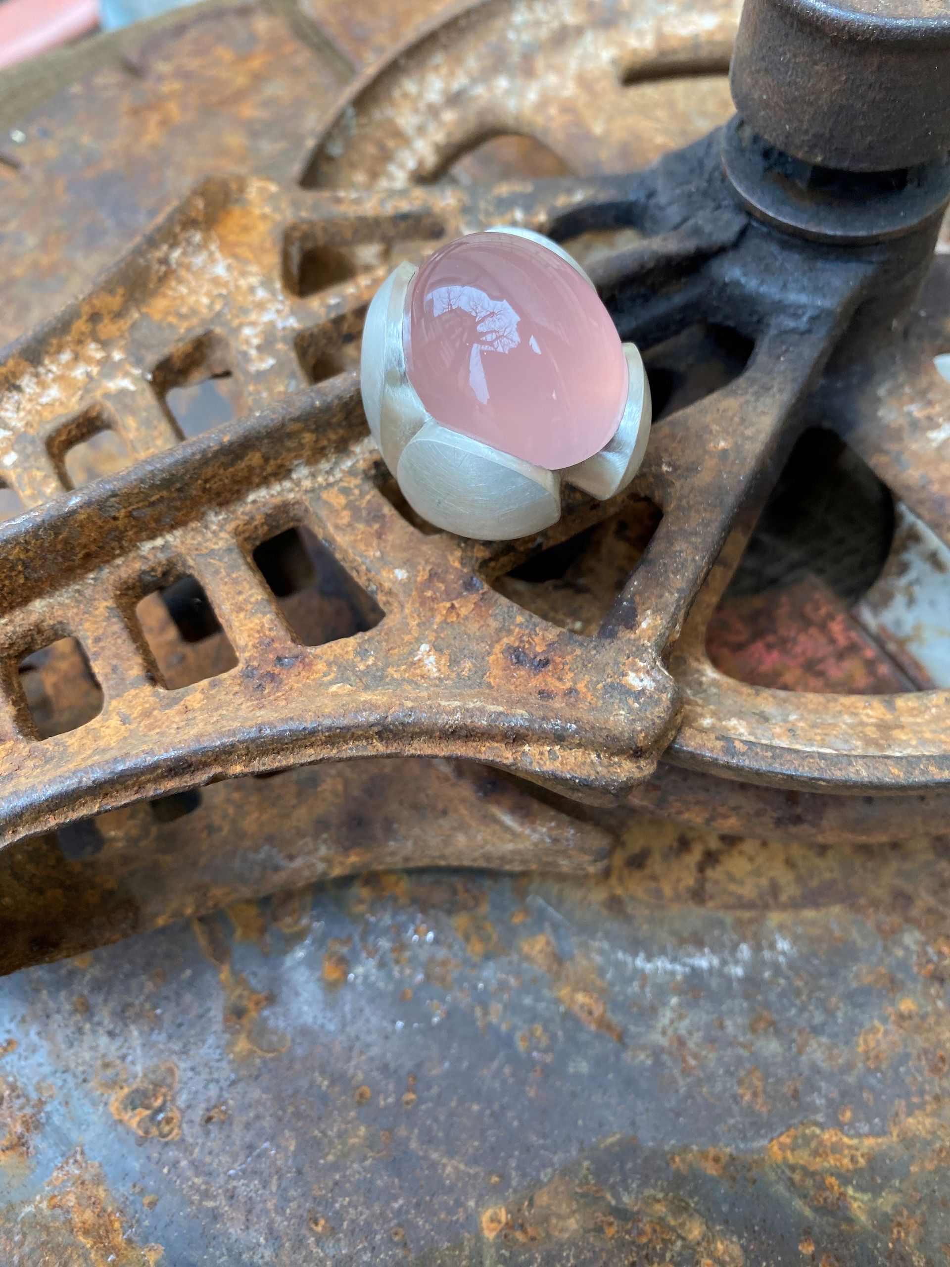 Rostiger Metallmechanismus mit einem kleinen rosa-weißen Edelstein oder Knopf oben drauf