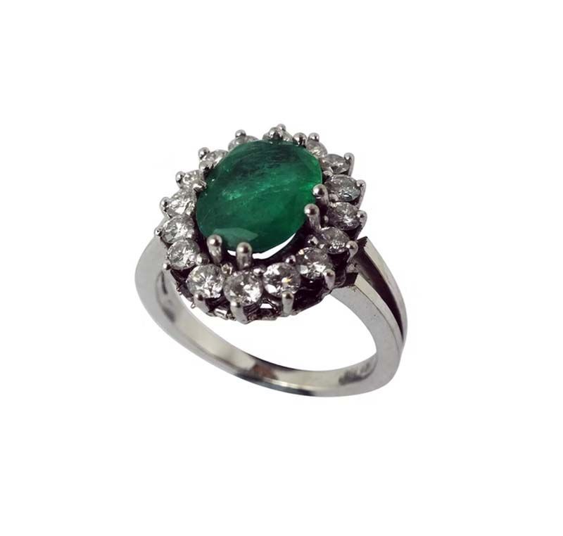 Smaragd- und Diamantring mit Halo-Fassung auf einem Silberband.