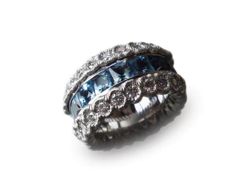 Silberner Ring mit blauen Edelsteinen und diamantähnlichen Akzenten auf weißem Hintergrund