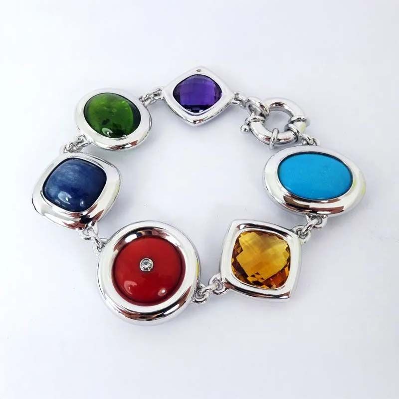 Farbenfrohes Edelsteinarmband mit sieben ovalen Steinen in Silberfassungen auf weißem Hintergrund