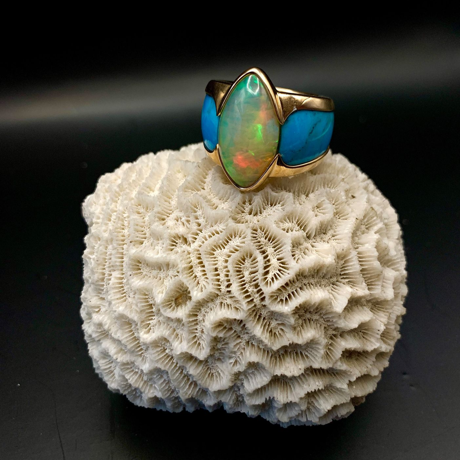 Opalring mit blauen Steinen auf einer weißen, korallenartigen Oberfläche