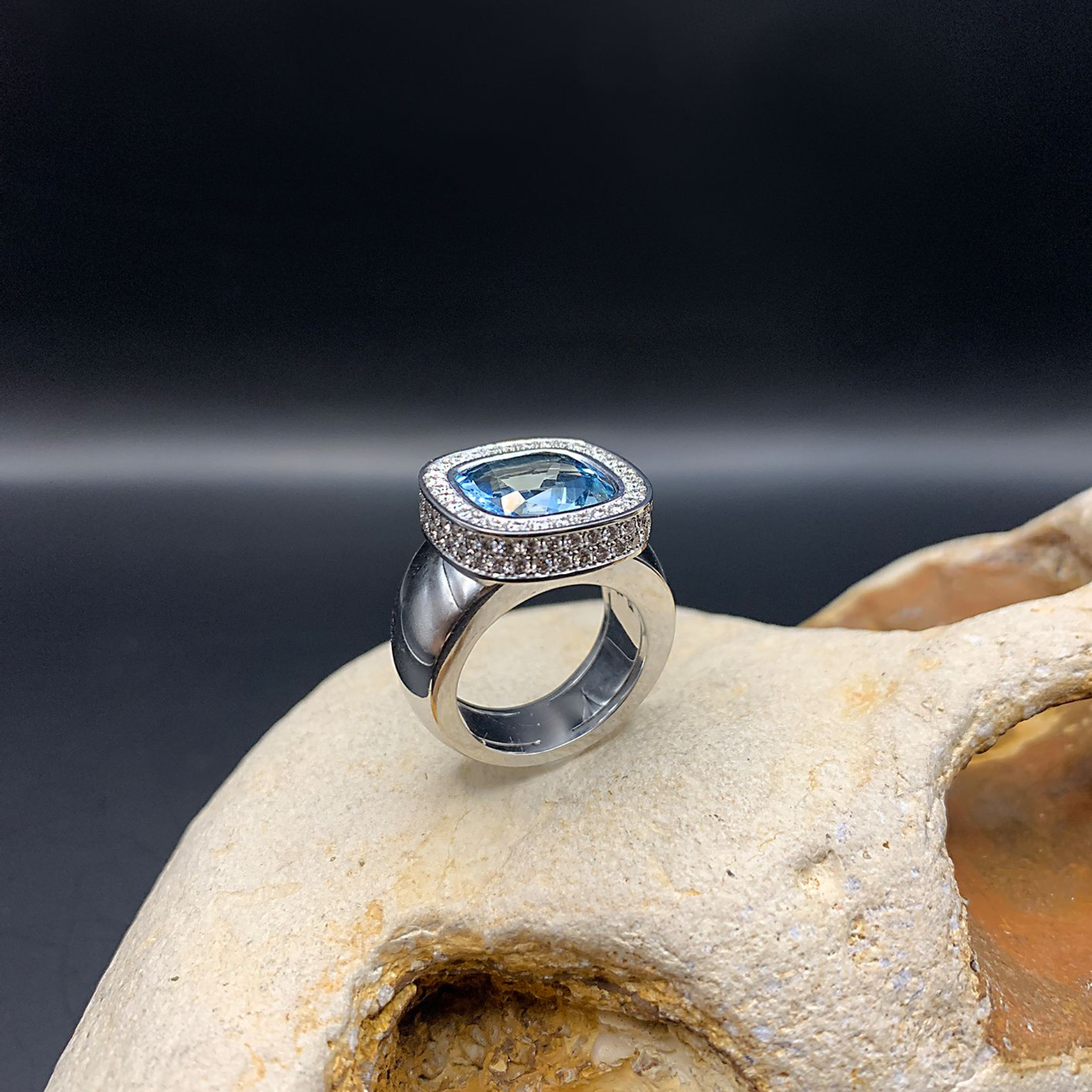 Silberring mit blauem Edelstein und Halo-Fassung auf hellem Stein