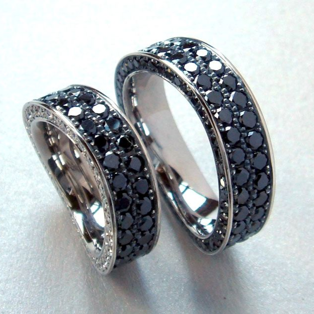 Zwei silberne Ringe mit schwarzen Steinen, die sich vor einem hellen Hintergrund aneinanderlehnen.