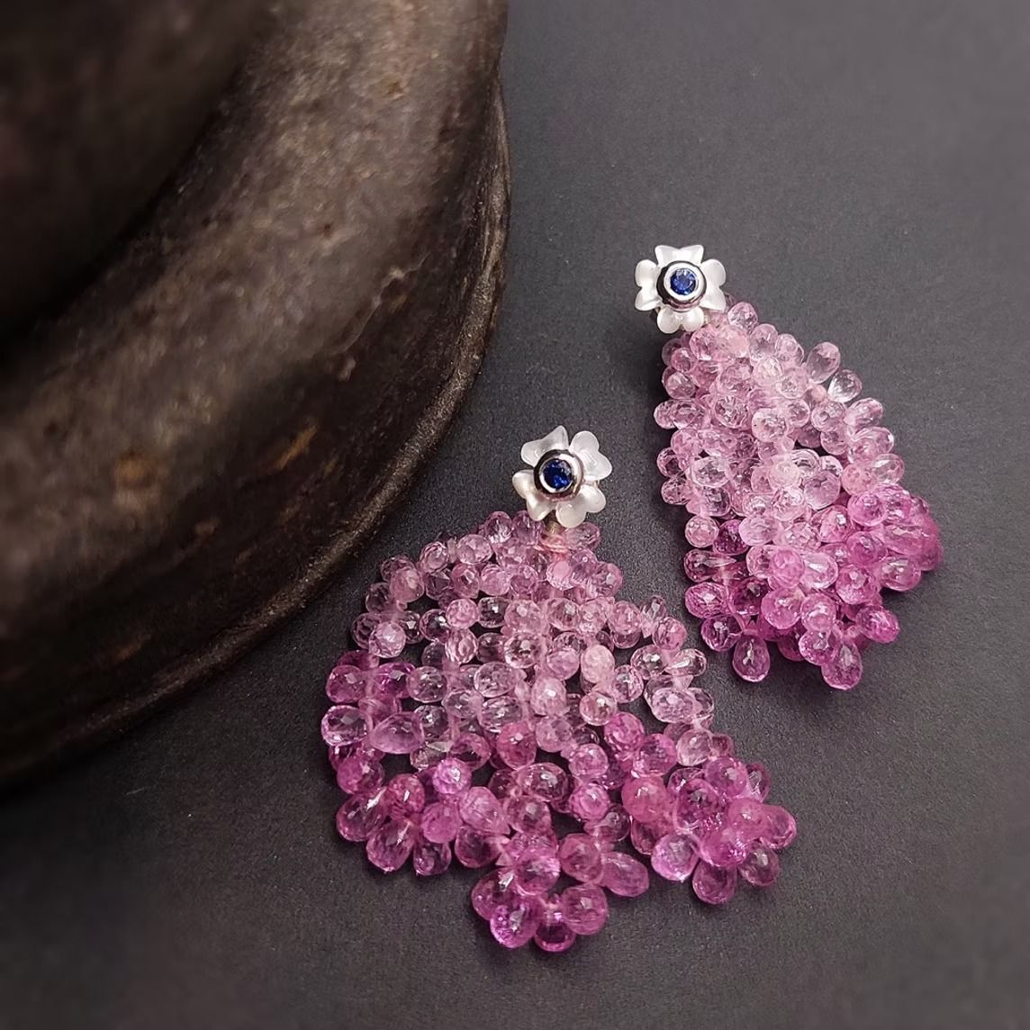 Ein Paar silberne Ohrringe mit gruppierten rosa Edelsteinperlen, die an einem floralen Ohrstecker baumeln.