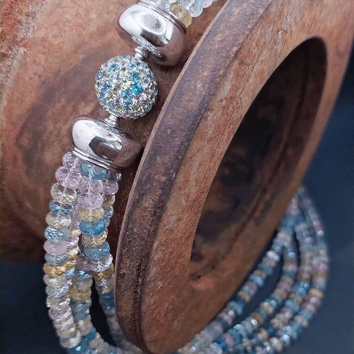 Holzspule mit darum gewickelten, schillernden Perlenarmbändern