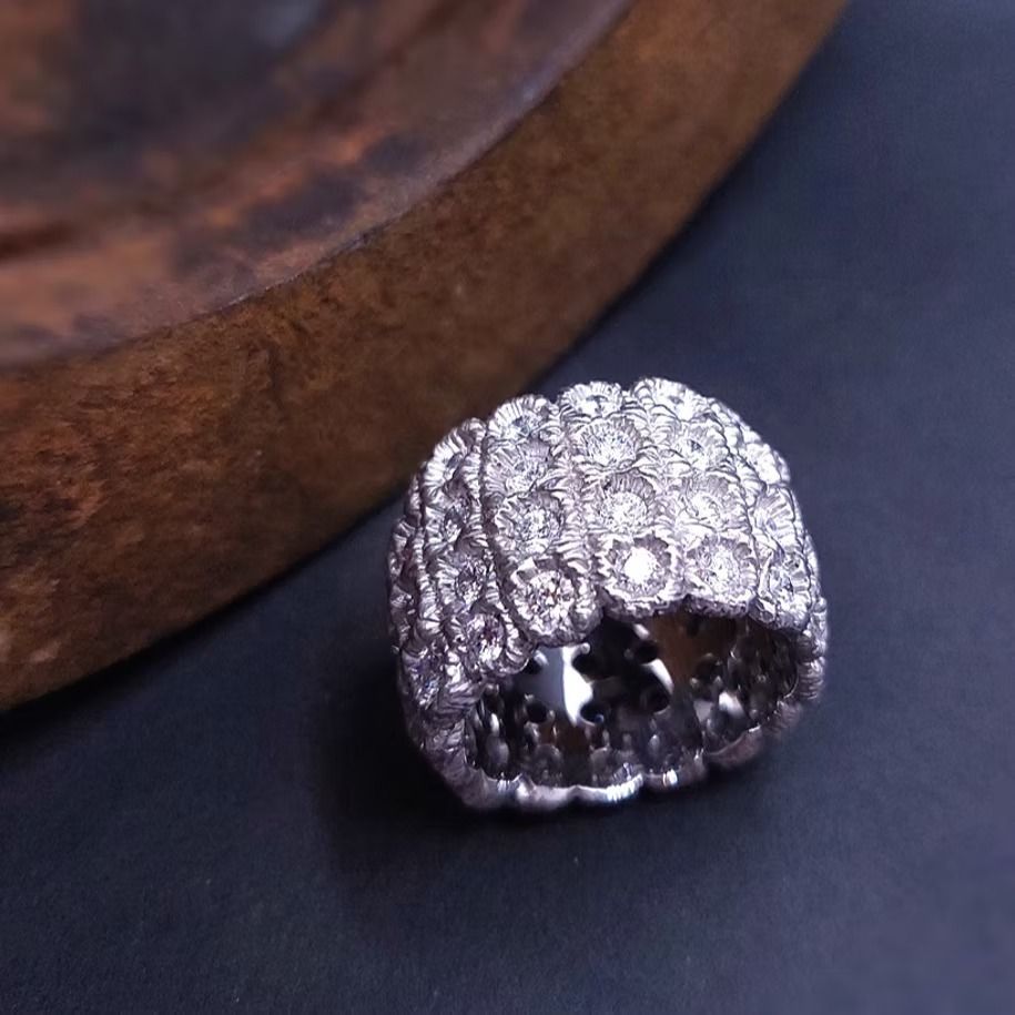 Nahaufnahme eines mit Diamanten besetzten Rings neben einer Holzschale auf dunklem Untergrund.