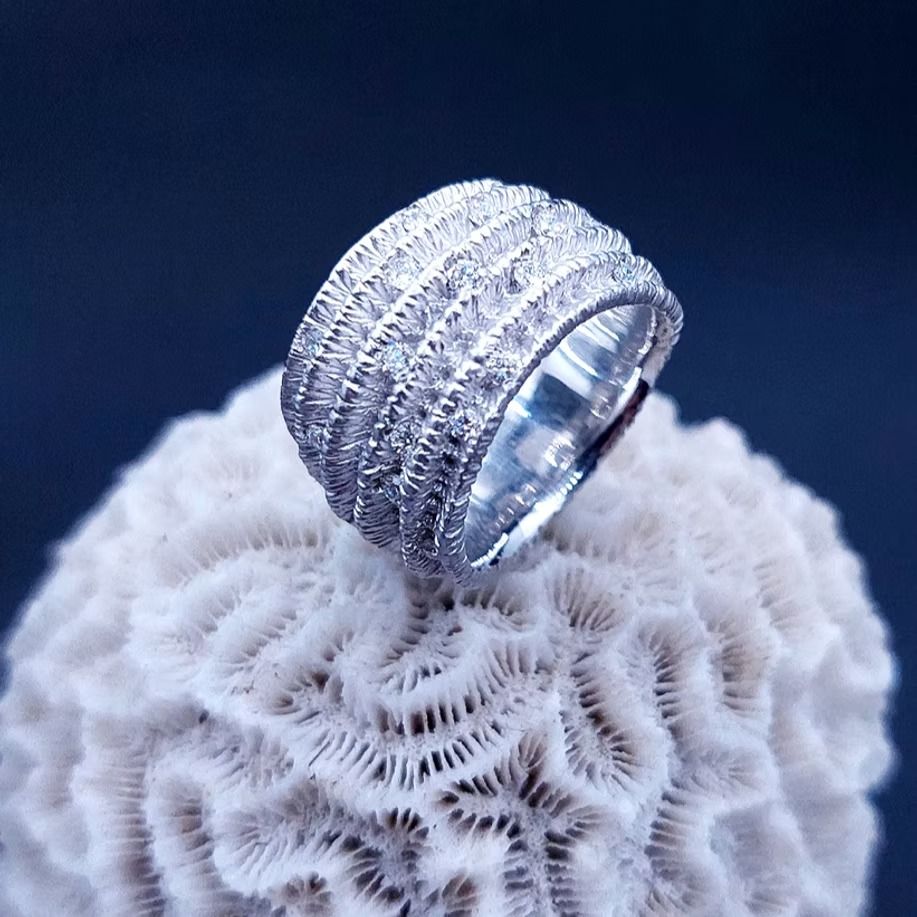 Ein silberner Ring, besetzt mit kleinen, glänzenden Edelsteinen, thront auf einer weißen Korallenformation.