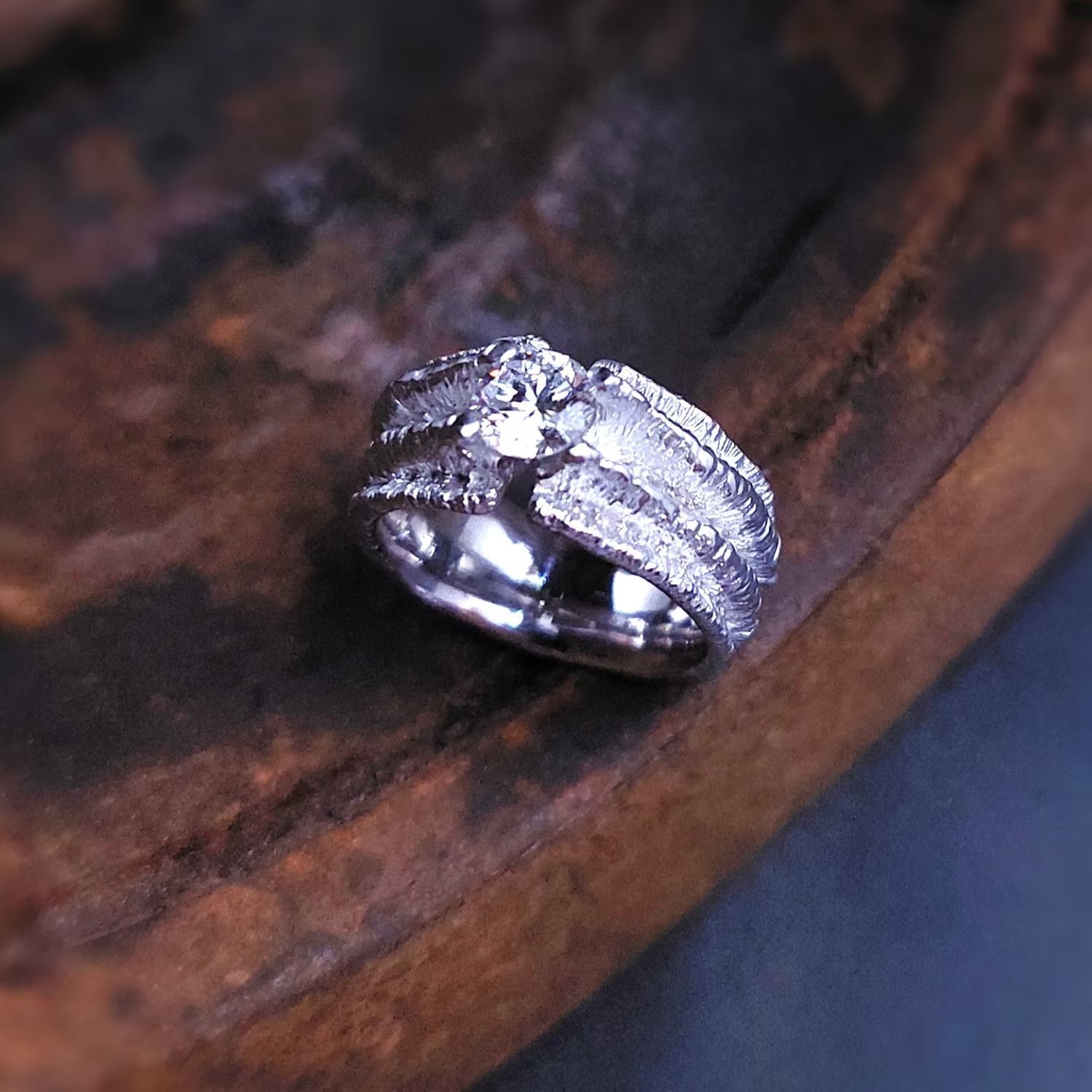 Silberner, krabbenförmiger Ring mit kleinen Edelsteinen auf dunklem Holz.