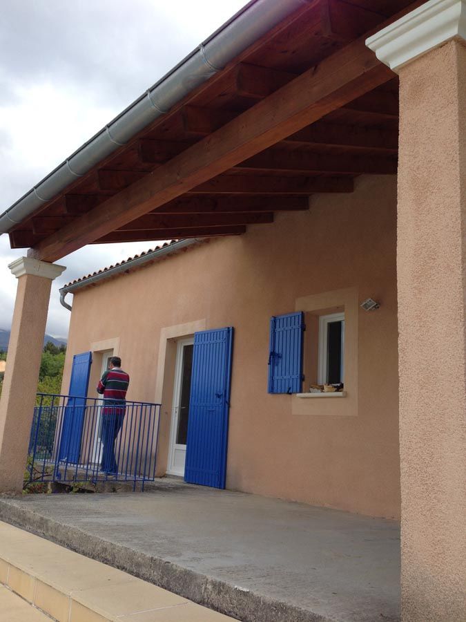 Maison orange avec volets bleus et terrasse