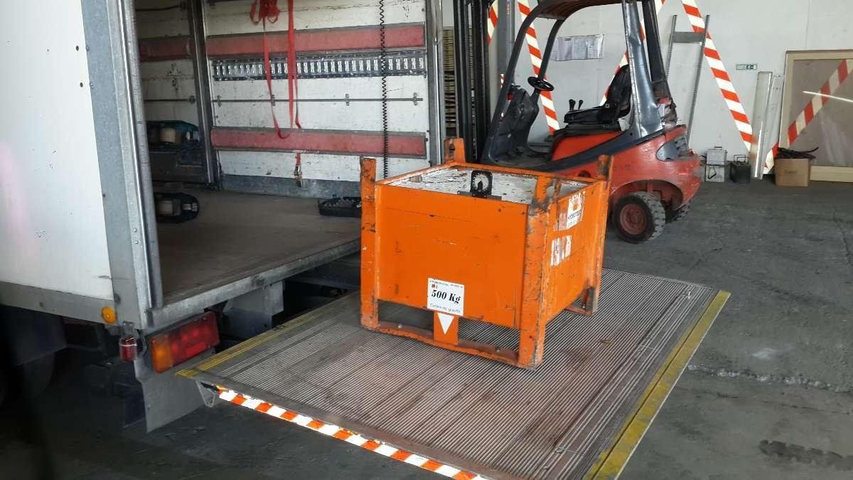 Un chariot élévateur orange charge un camion dans la zone de quai d'un entrepôt