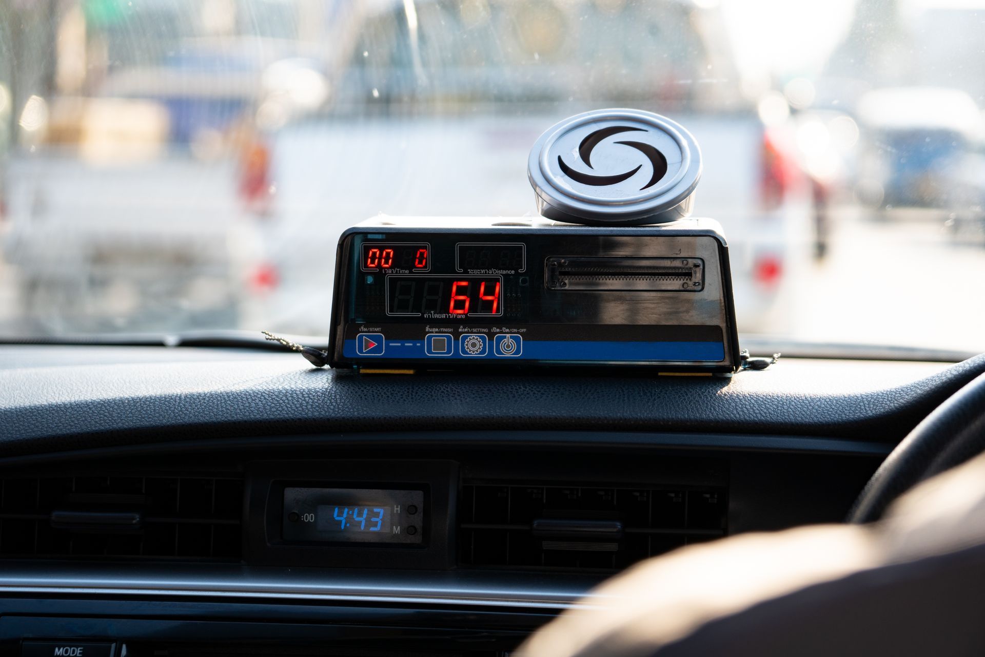 Tableau de bord du taxi affichant 6,4 V sur un compteur numérique avec un dispositif rond au-dessus, vu de l'intérieur du véhicule