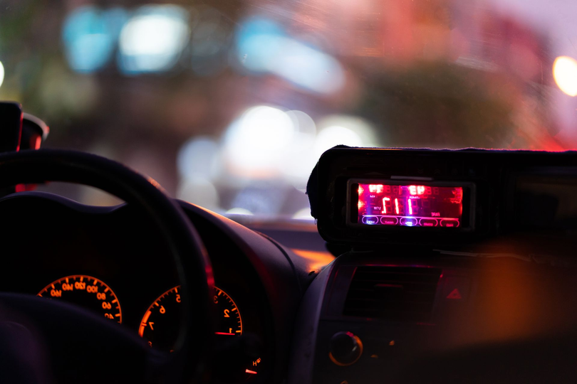 Tableau de bord de voiture la nuit, avec cadrans éclairés et rétroviseur rougeoyant, lumières de la ville floues à l'extérieur
