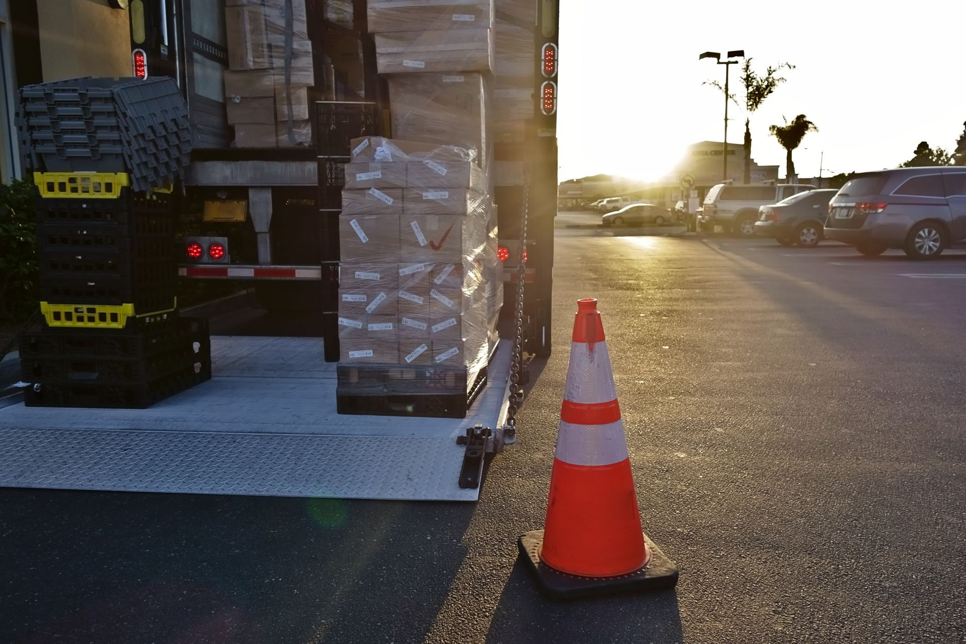 Cône de signalisation orange à côté de cartons empilés sur le hayon d'un camion.