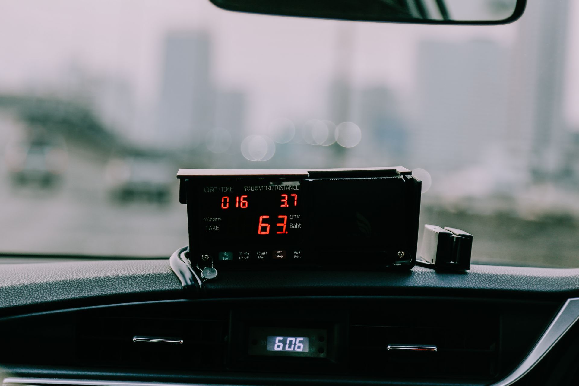 Tableau de bord de voiture avec affichage numérique rouge indiquant la vitesse dans un décor de rue urbaine flou