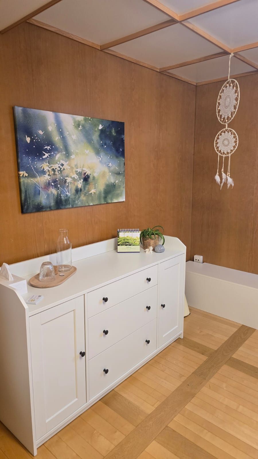 Über der Kommode im Zimmer hängt ein Gemälde an der Wand.