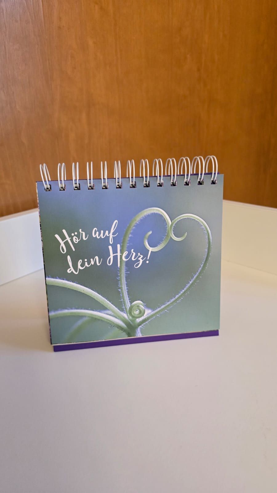 Auf einem Tisch liegt ein kleines Notizbuch mit einem Herz darauf.