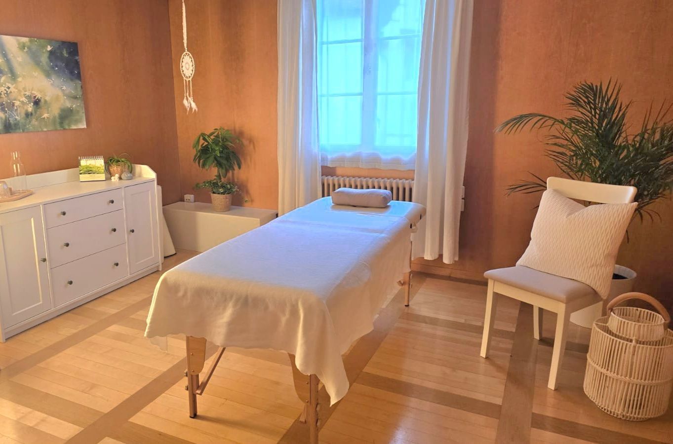 In einem Raum steht neben einem Stuhl eine Massageliege.