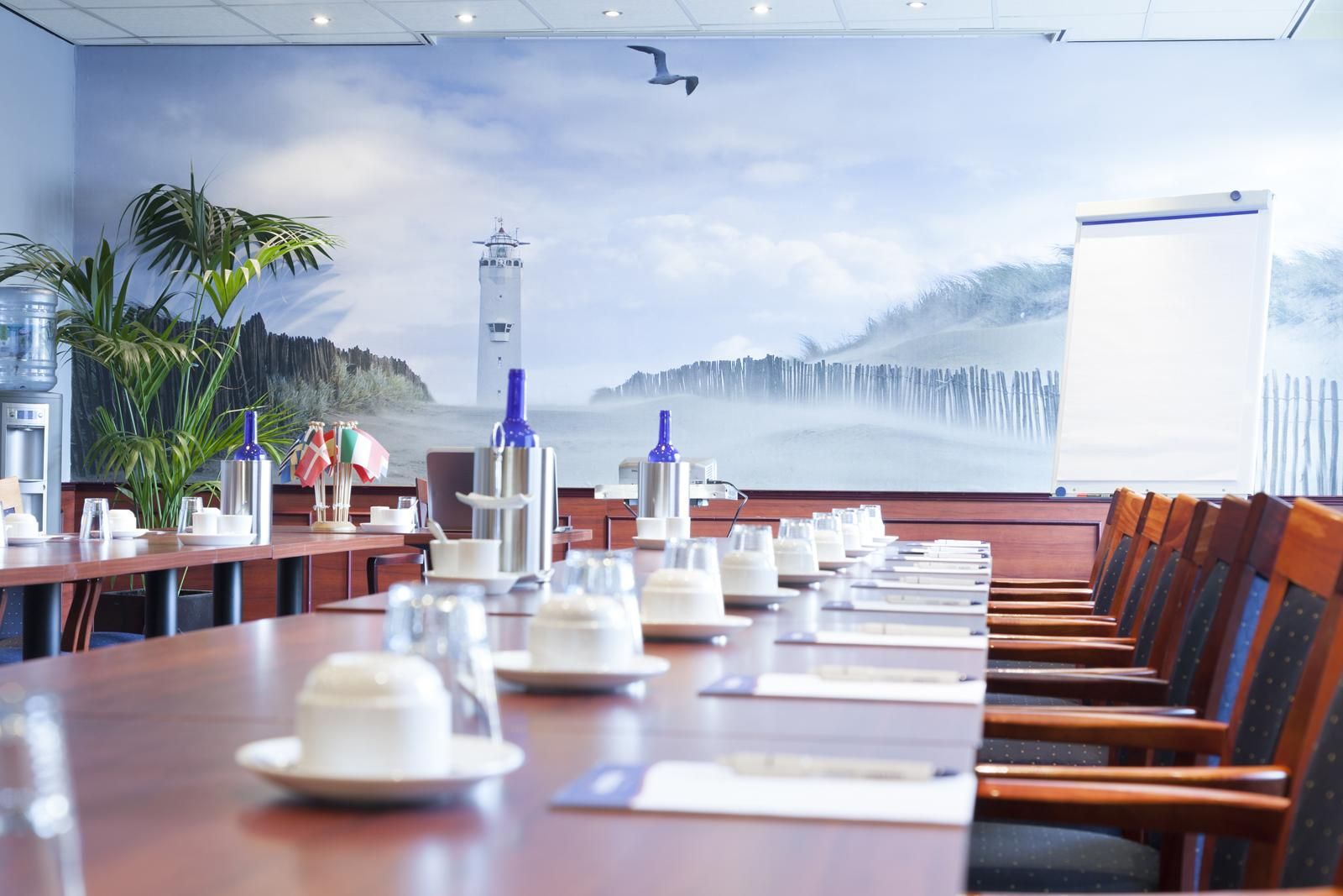 Een conferentieruimte met een lange tafel en stoelen en een vuurtoren aan de muur.