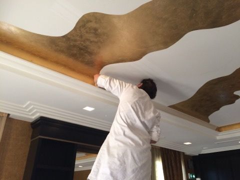 Artisan en train de mettre papier peint doré sur plafond