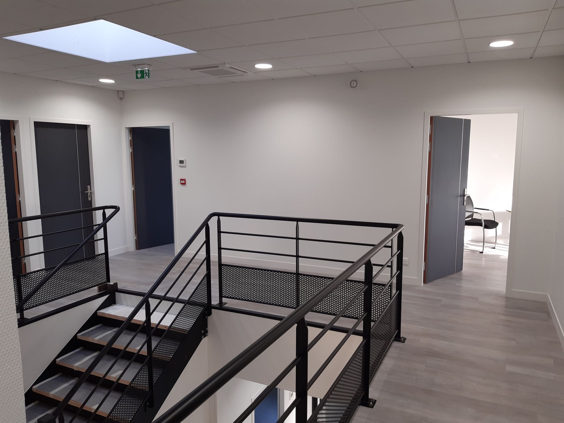 Photo du haut d'escalier avec garde-corps en fer noir