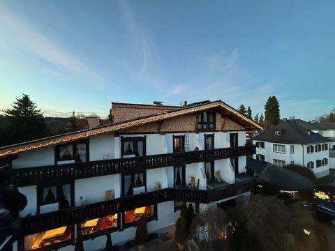 Ein Bauarbeiter in Warnweste und orangefarbenem Schutzhelm montiert mit einer Bohrmaschine Metalldachplatten.