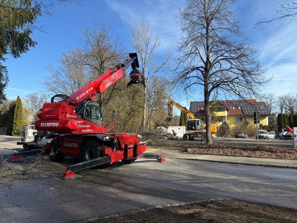 Ein roter Manitou-Kran mit Greiferaufsatz und ein gelber Bagger sind in einem Wohngebiet mit Baumfällarbeiten beschäftigt.