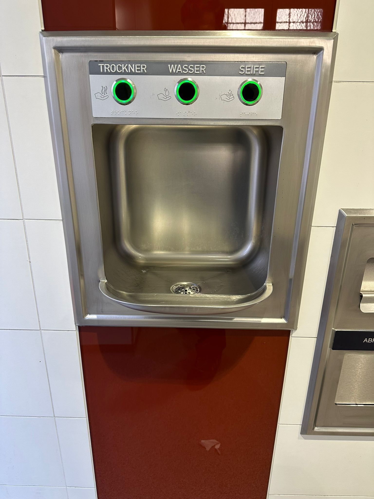 Nahaufnahme eines Edelstahl-Handwaschbeckens in einer öffentlichen Toilette.