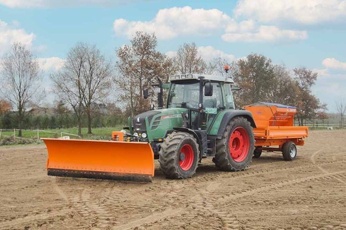 Ein Traktor mit daran befestigtem Pflug pflügt ein Feld.